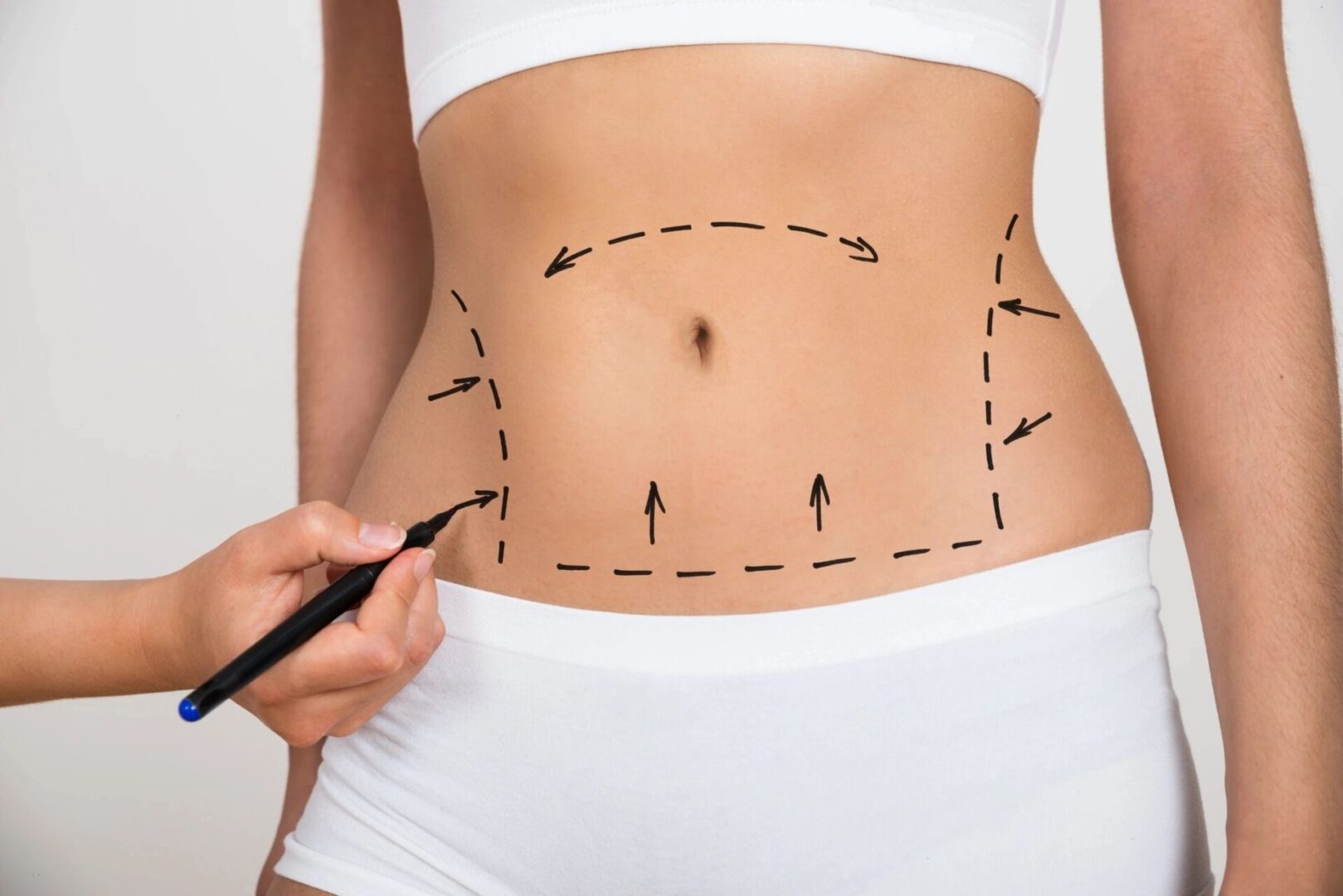 A woman is drawing lines on her stomach.